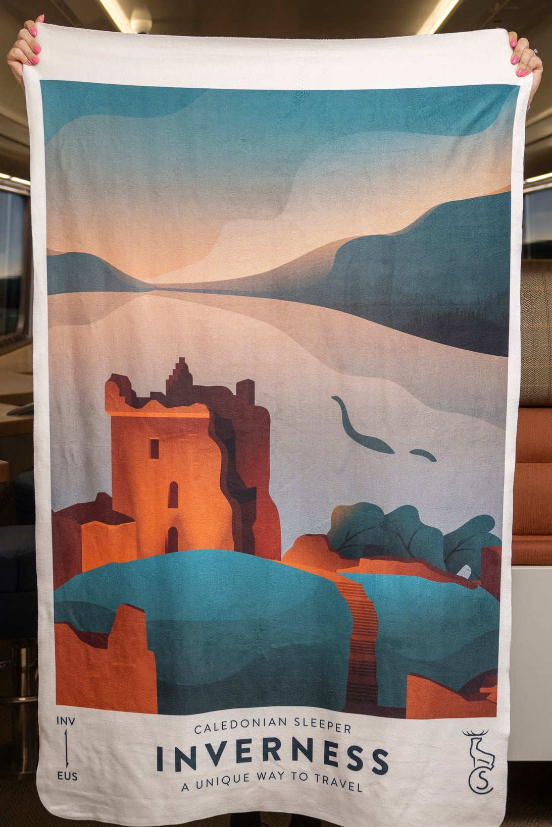 A person holds a full size Caledonian Sleeper Inverness Fleece Blanket